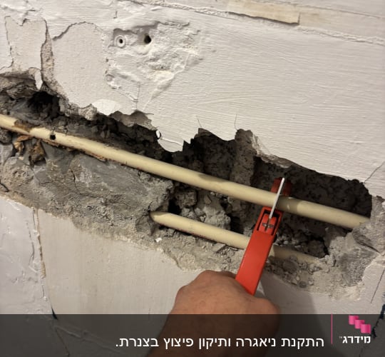 תיקון צינור בקיר עם כלי עבודה אדום